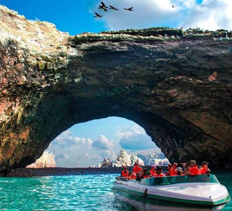 Lancha navegando bajo un arco de roca en las Islas Ballestas