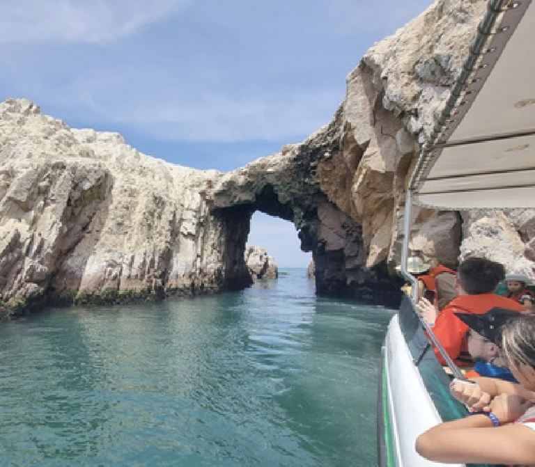 Lancha pasando por un arco de roca en las Islas Ballestas
